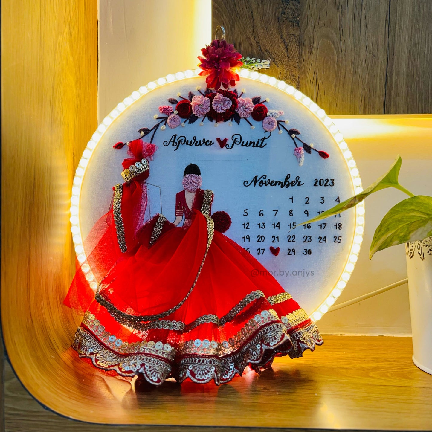 Decorative calendar with a couple in red gowns on a wooden surface.