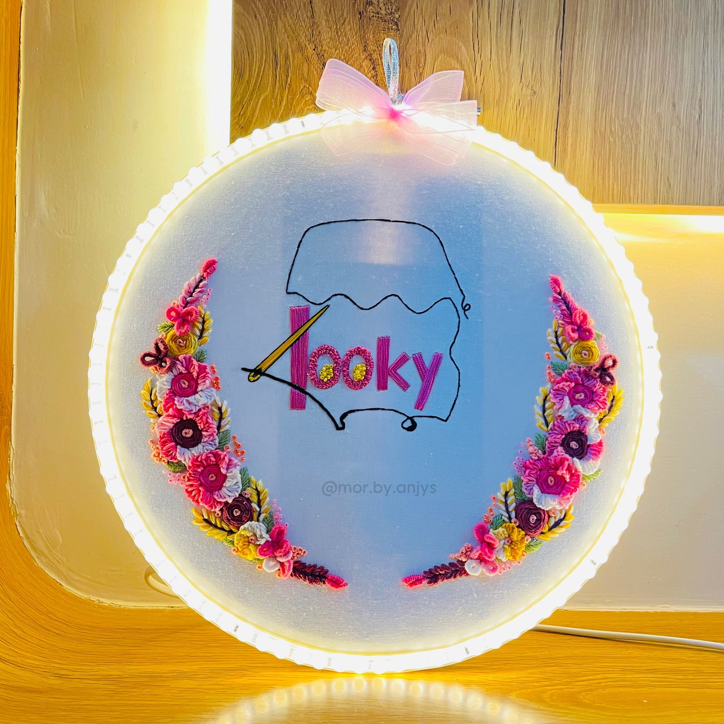 Embroidery hoop with floral design and 'hooky' text on a wooden surface