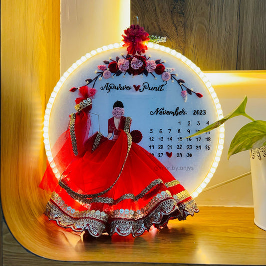 Decorative calendar with a couple in red gowns on a wooden surface.