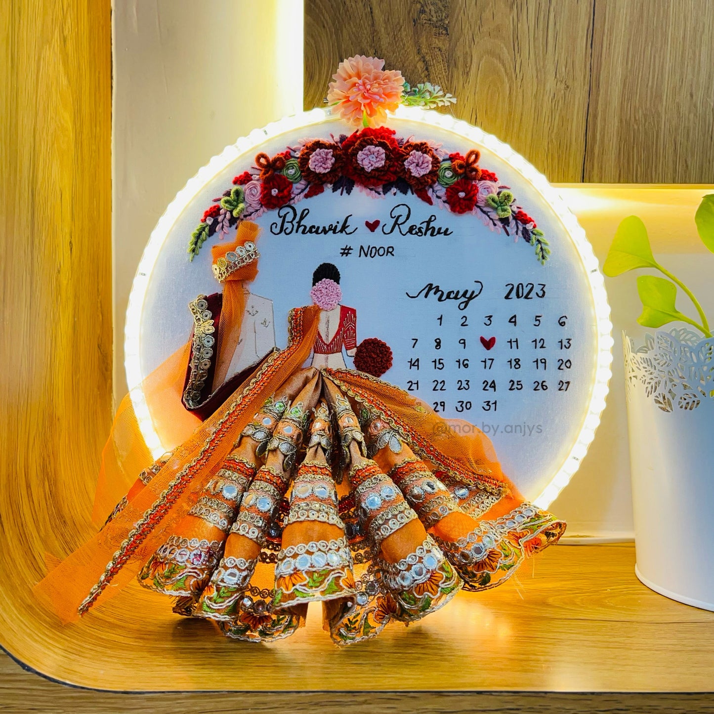 Decorative wall hanging with a couple illustration and calendar on a wooden surface