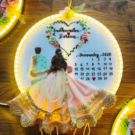 Decorative calendar with LED lights featuring a couple and floral design on a wooden surface.