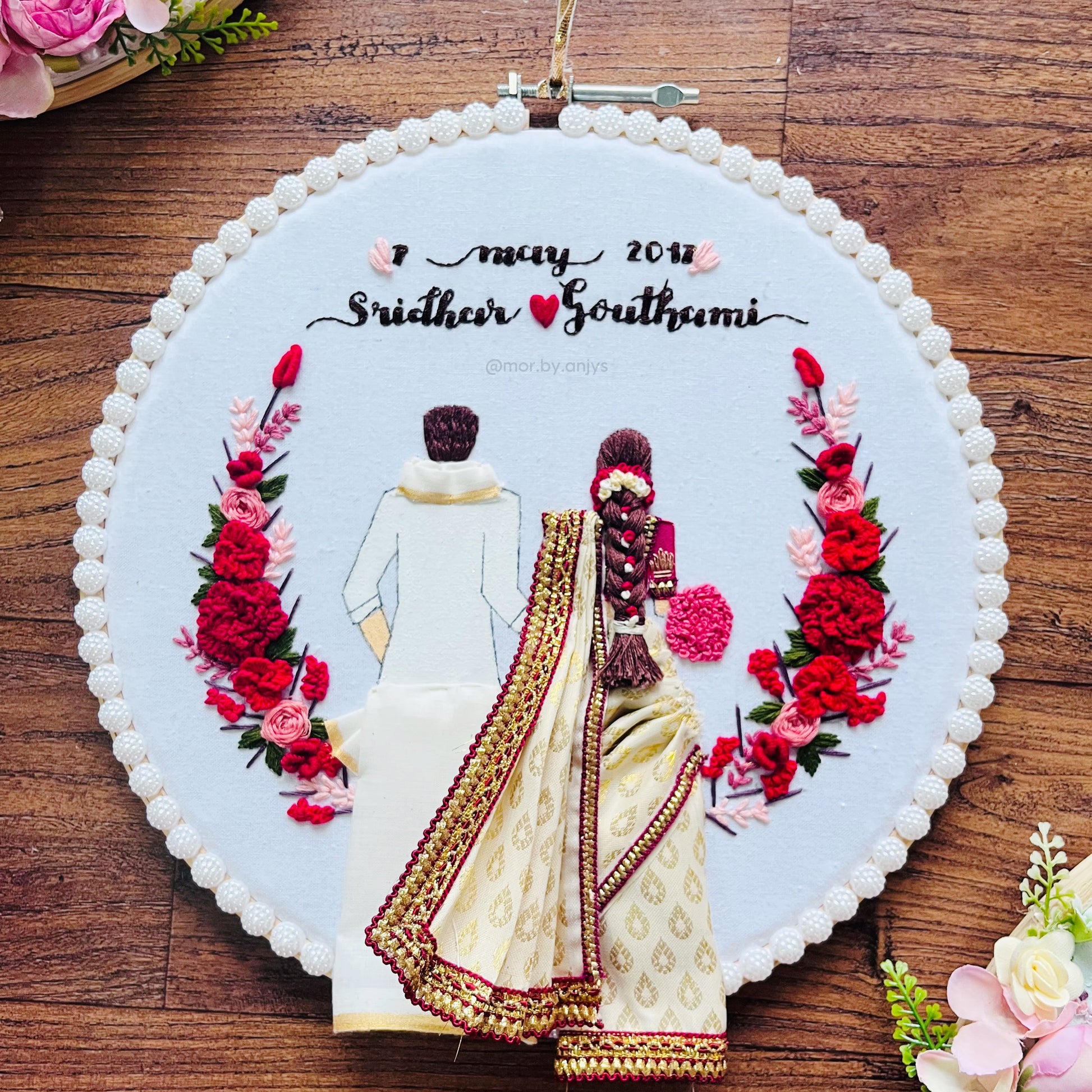 Embroidery of a couple with flowers on a wooden surface for south indian wedding