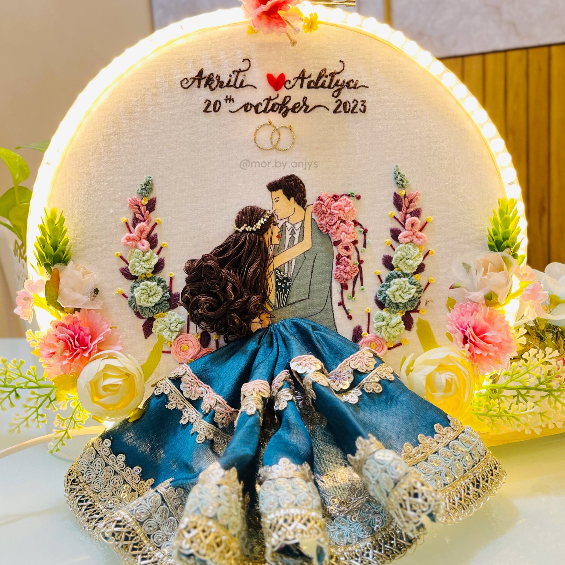 Decorative item with a couple illustration, flowers, and text on a round frame.