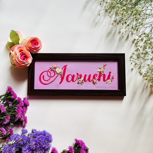 Framed nameplate surrounded by flowers on a light background