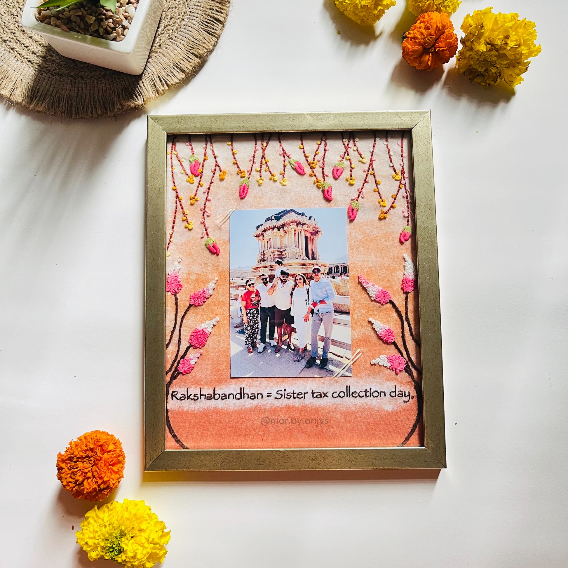 Decorative photo frame with a family photo and floral design on a white surface with flowers around.