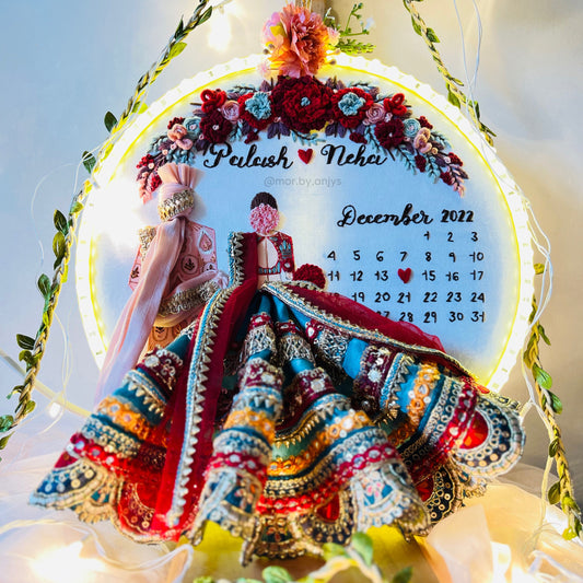 Decorative calendar with traditional attire and floral design, surrounded by lights and greenery.