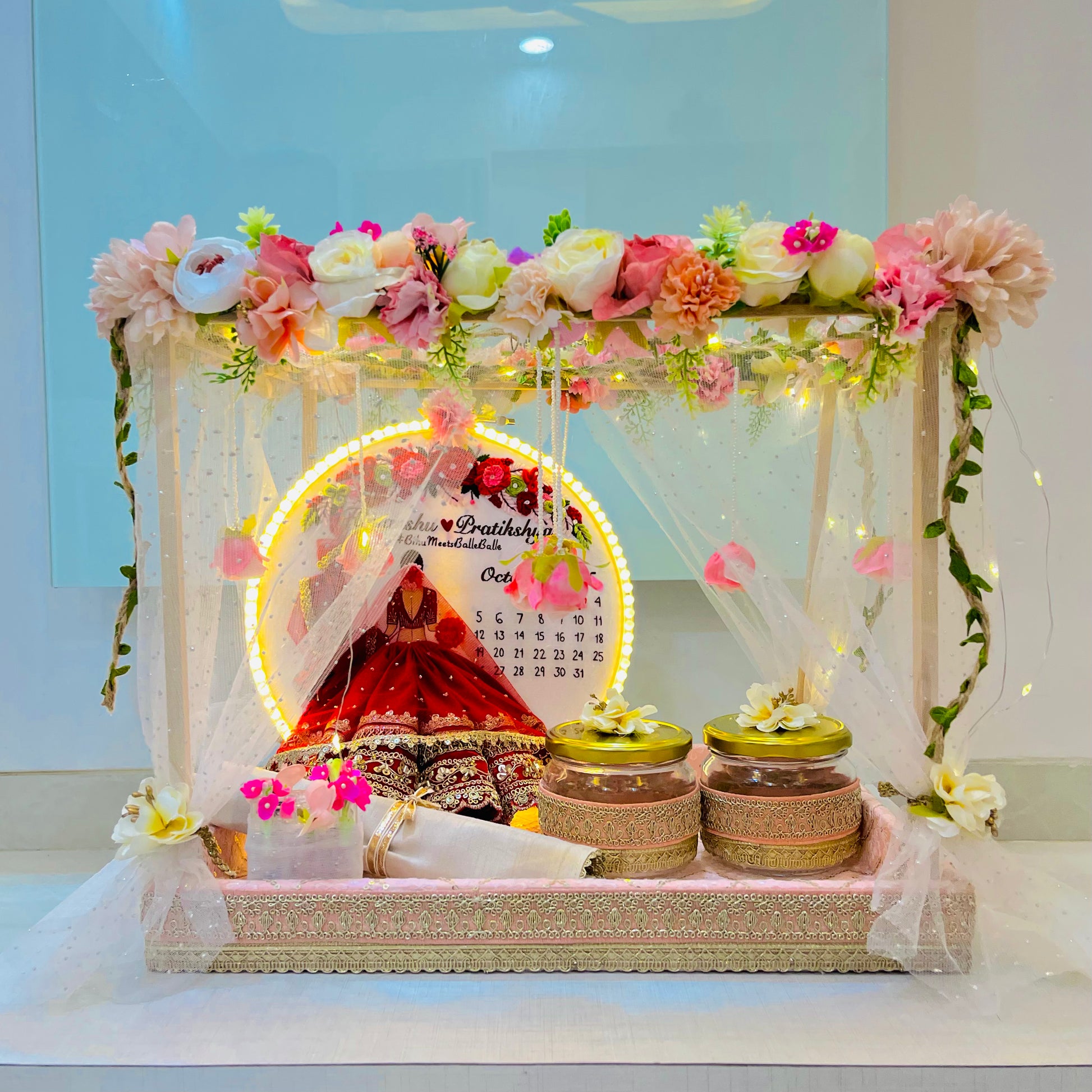 Decorative setup with flowers, jars, and a calendar on a white surface.